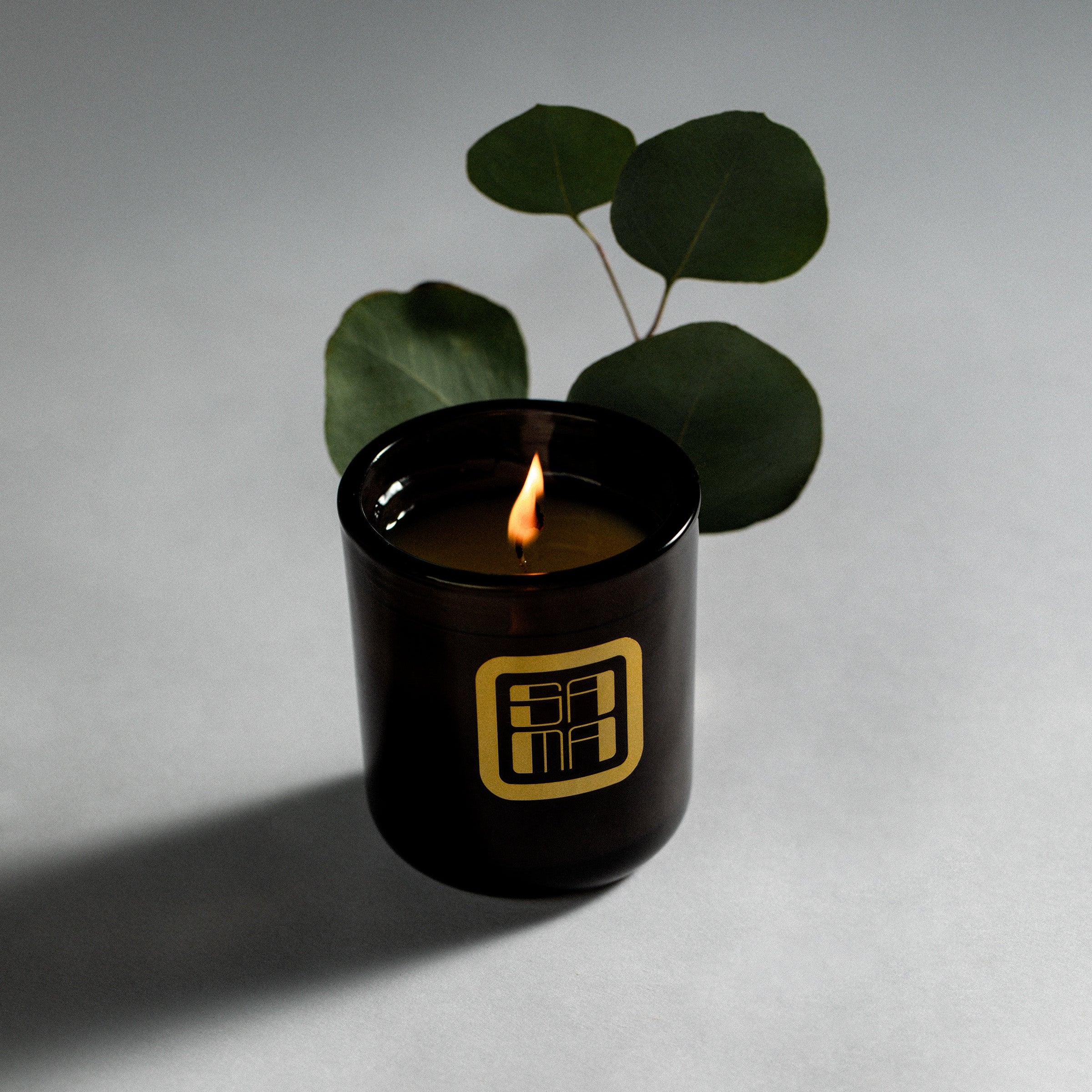 Black candle with a gold logo on a gray background
