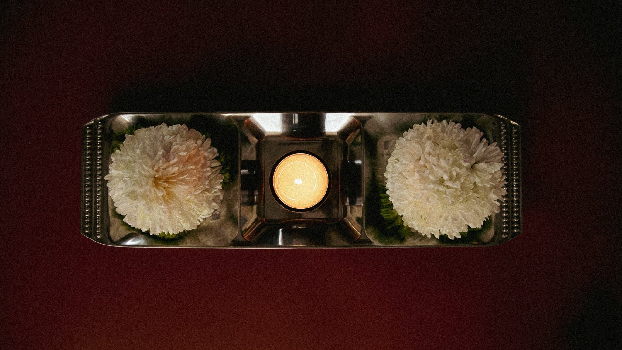 Decorative arrangement with flowers and a candle on a dark background