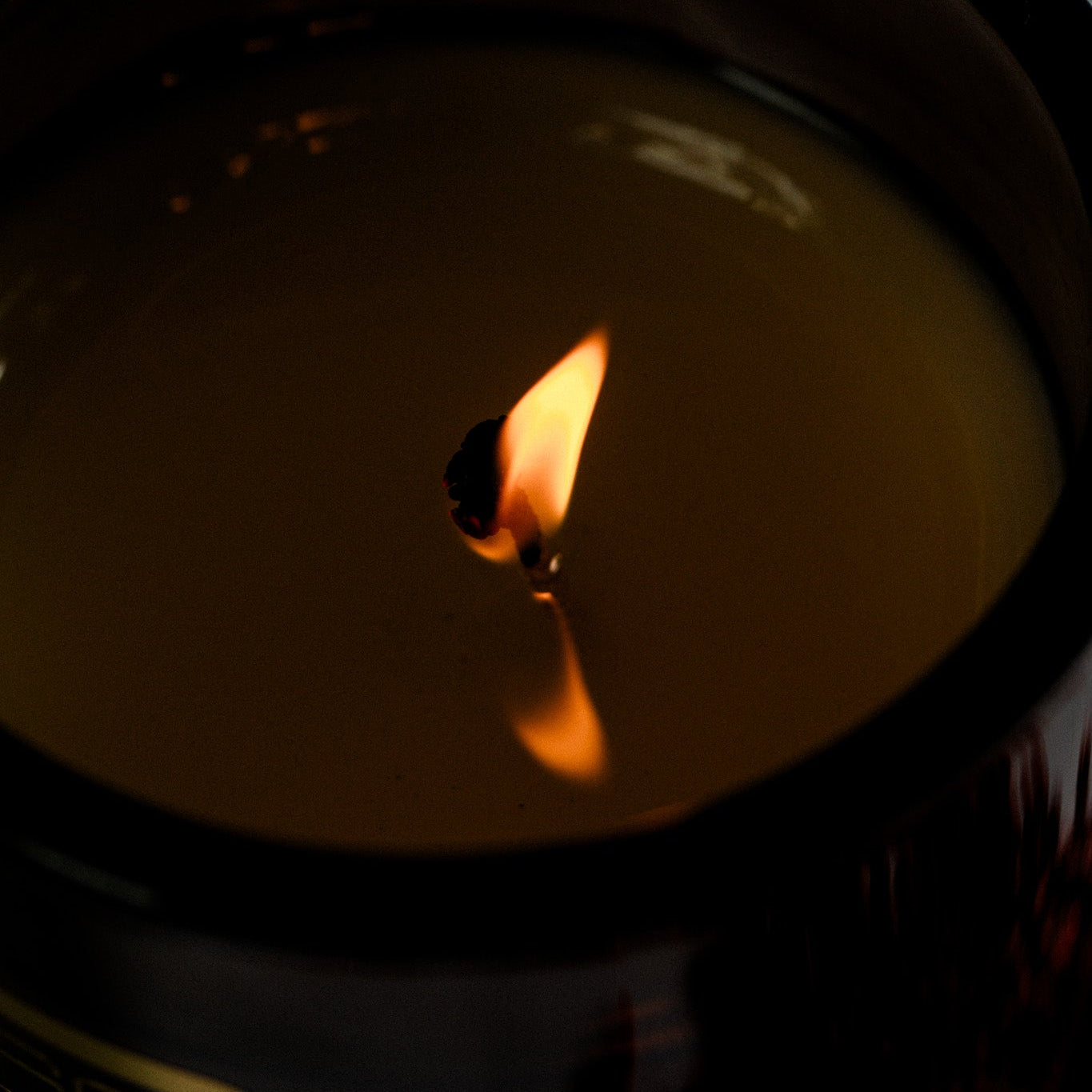 Close-up of a candle with a small flame against a dark background