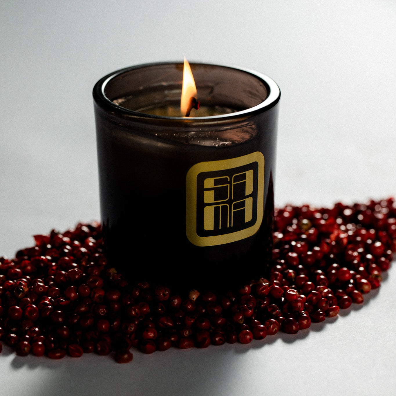 Black candle with a gold logo on a white background