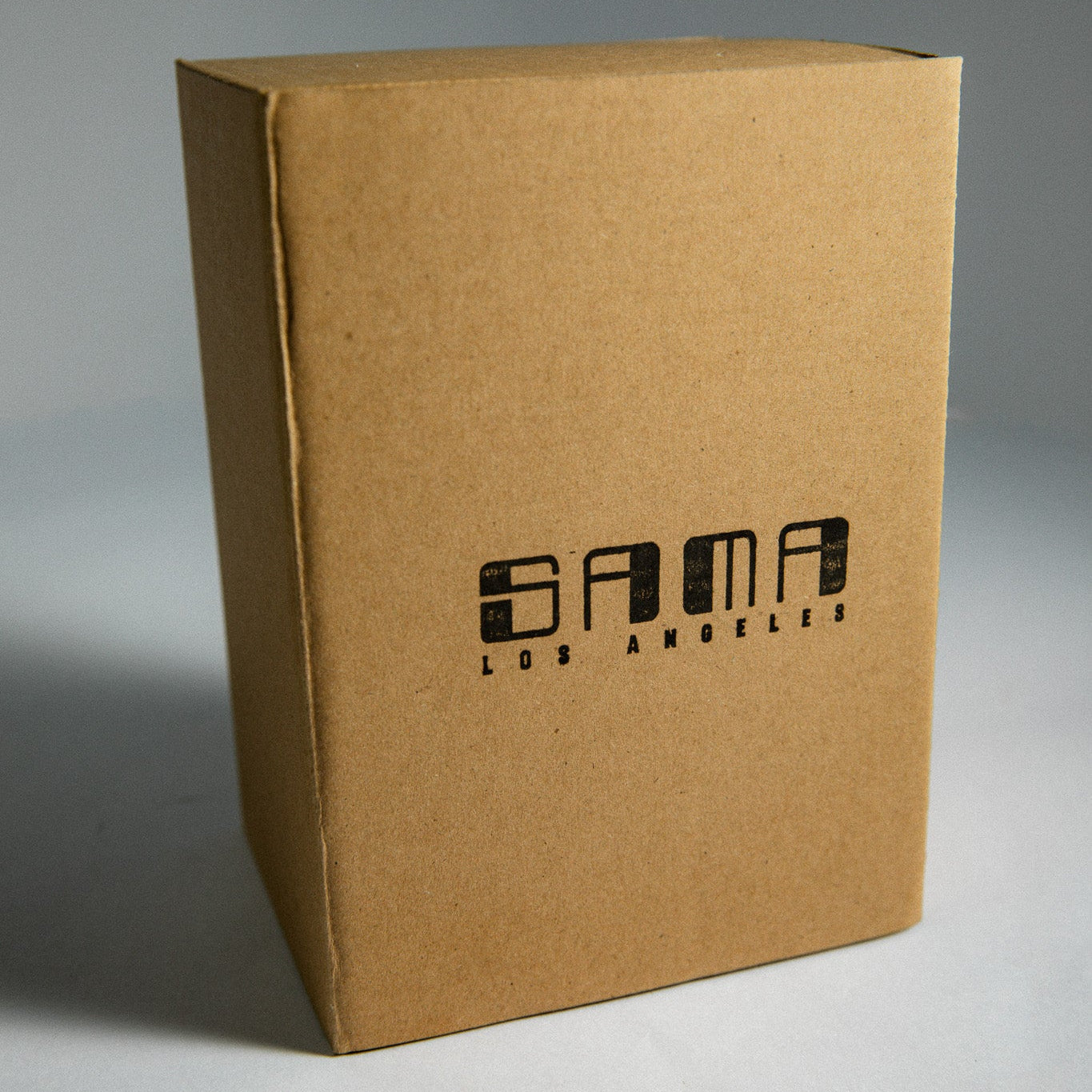 Brown cardboard box with 'Sama Los Angeles' branding on a gray background