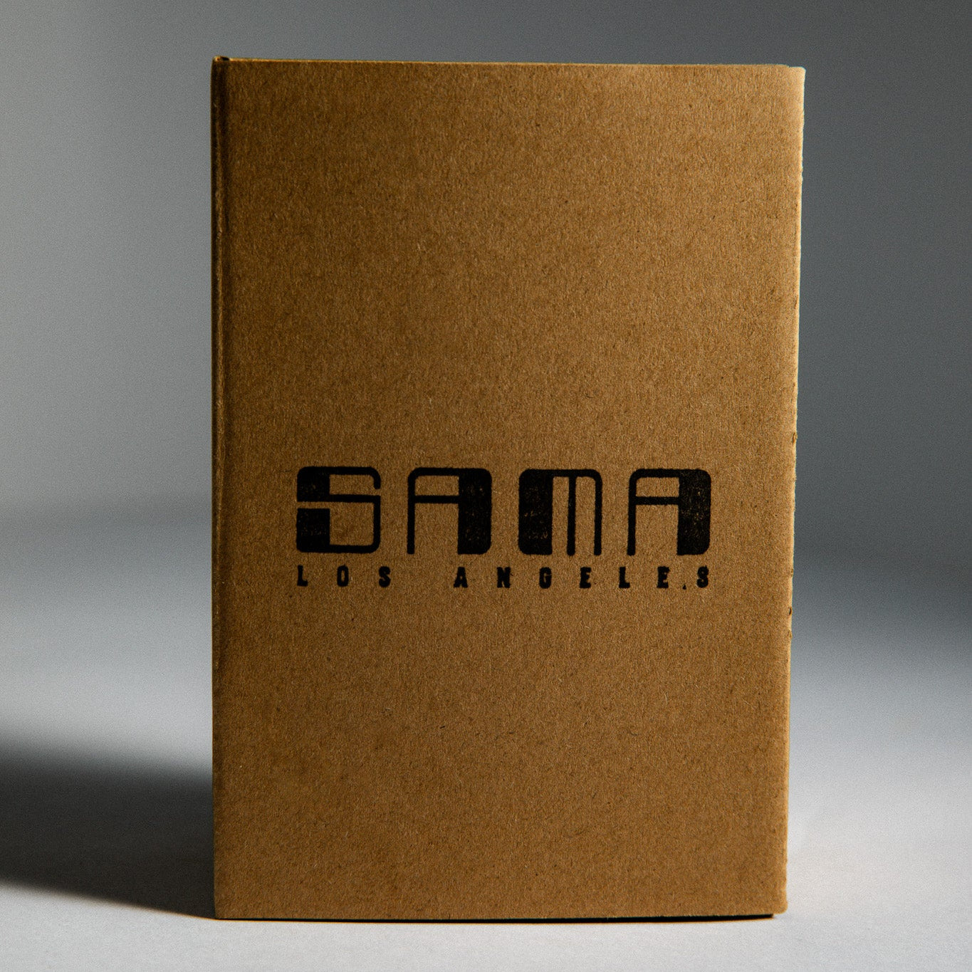 Brown cardboard box with 'SAMA LOS ANGELES' branding on a gray background