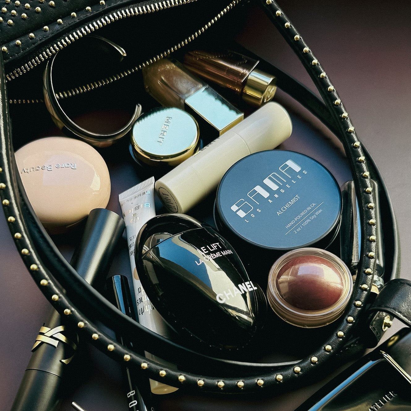 Makeup bag with various cosmetic items including lipsticks and a mirror on a dark background