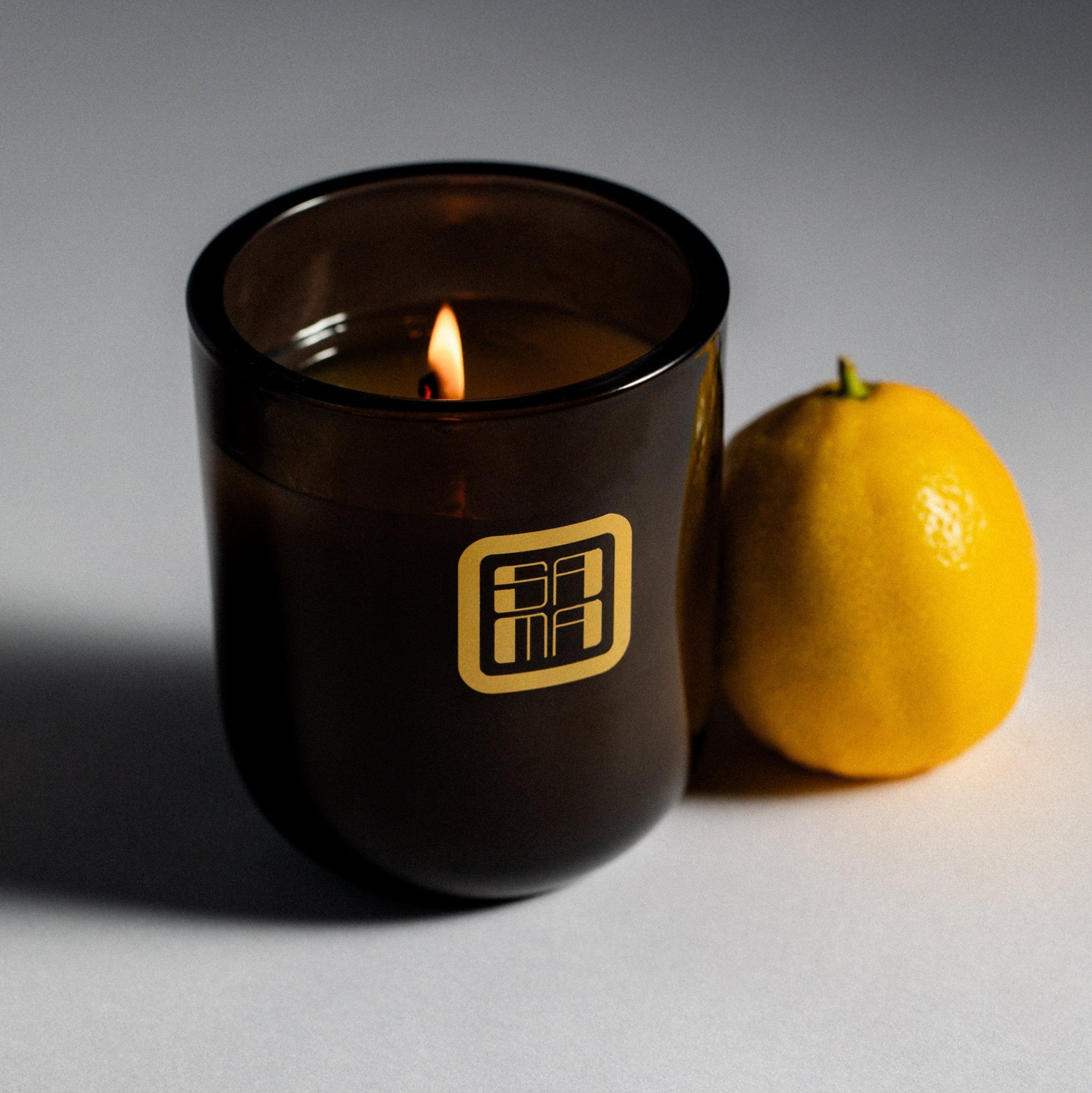 Black candle with a lemon on a gray background