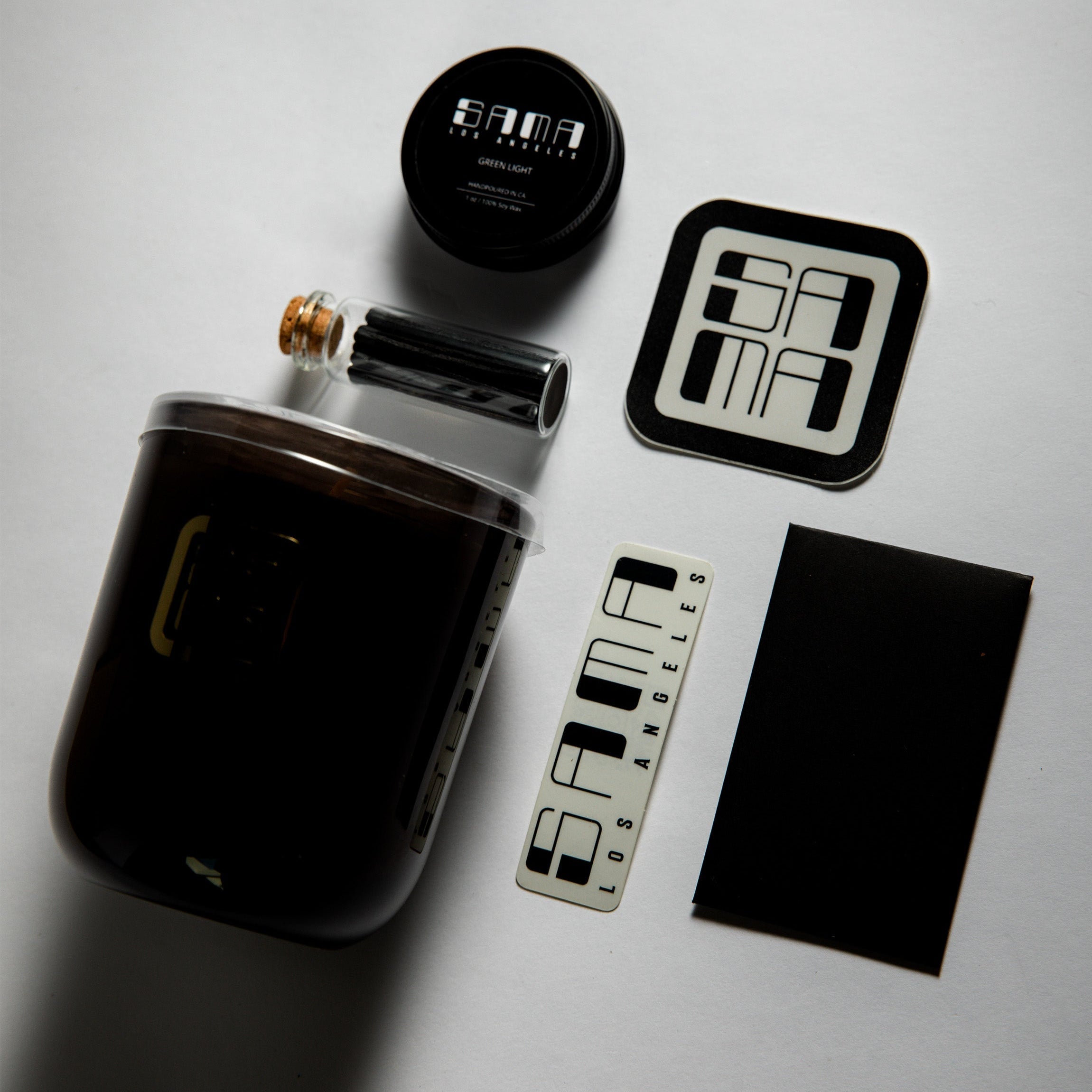 Collection of Sama Los Angeles products including a metal flask, container, and branded items on a light gray background.
