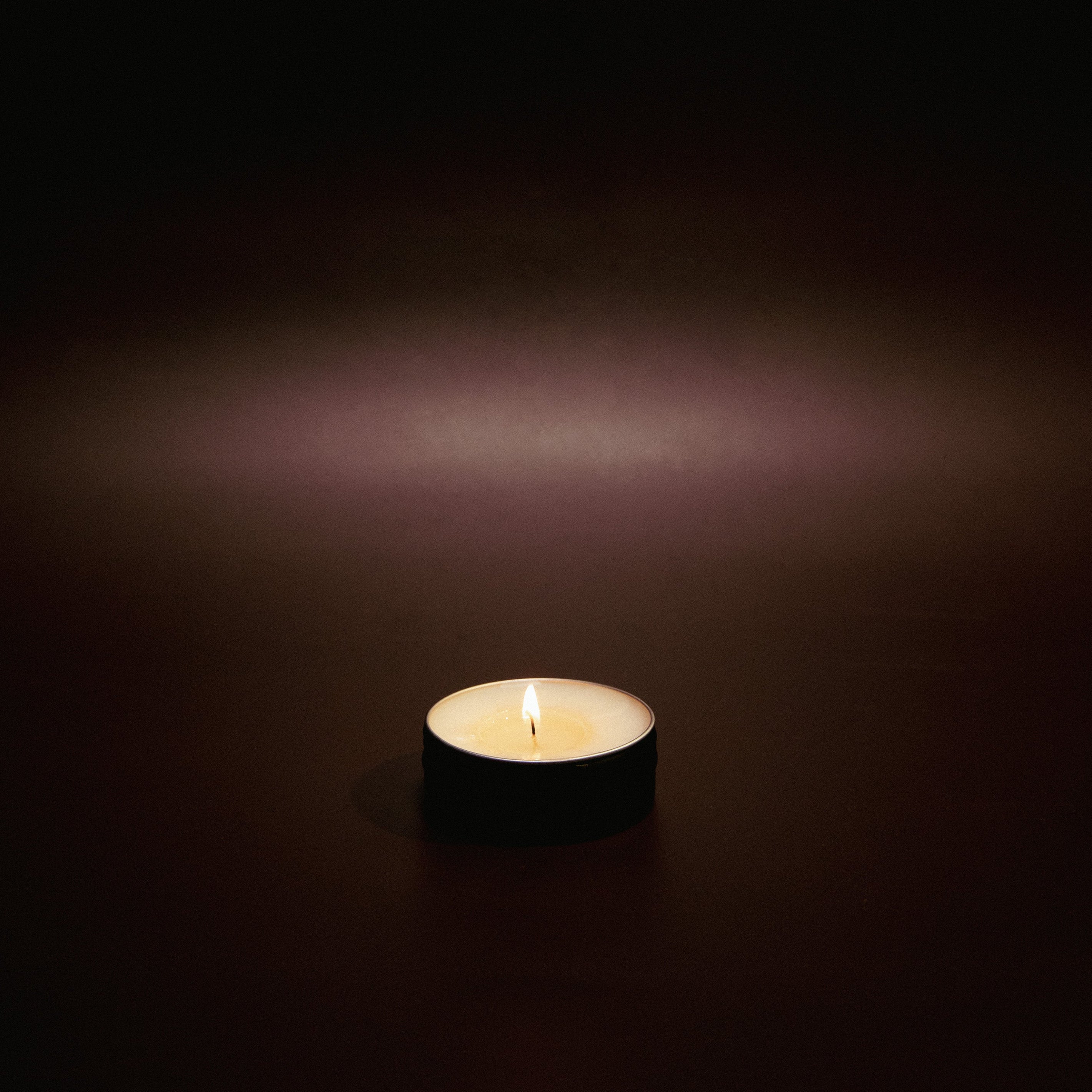 Single lit candle in a dark setting